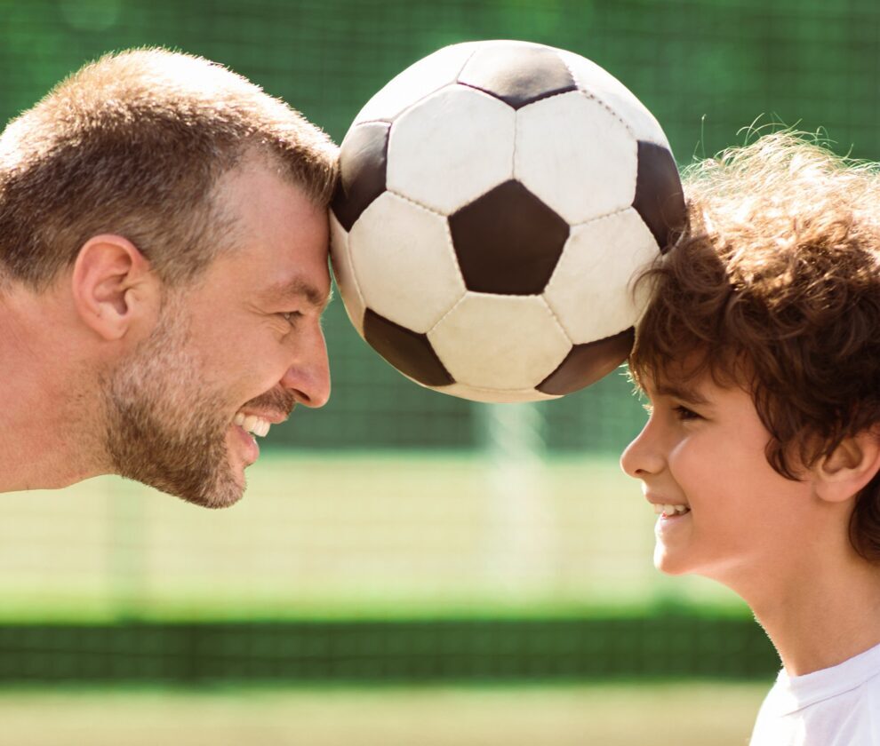Man holding ball between two heads with little boy