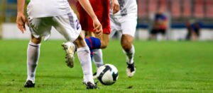 Silny defensor w niskiej pozycji startowej, gotowy do pojedynku biegowego na skrzydle boiska w trakcie meczu ligowego.